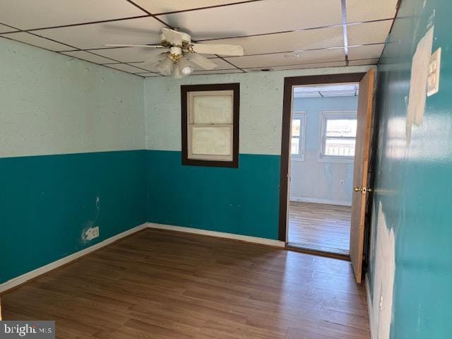 spare room featuring ceiling fan, a drop ceiling, wood finished floors, and baseboards