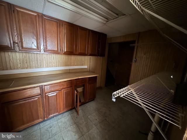 interior space featuring brown cabinetry, wooden walls, and light countertops