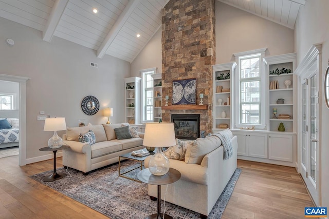 living room with beam ceiling, high vaulted ceiling, light hardwood / wood-style floors, wooden ceiling, and a fireplace