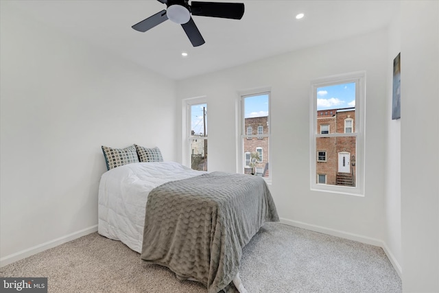 carpeted bedroom featuring multiple windows and ceiling fan