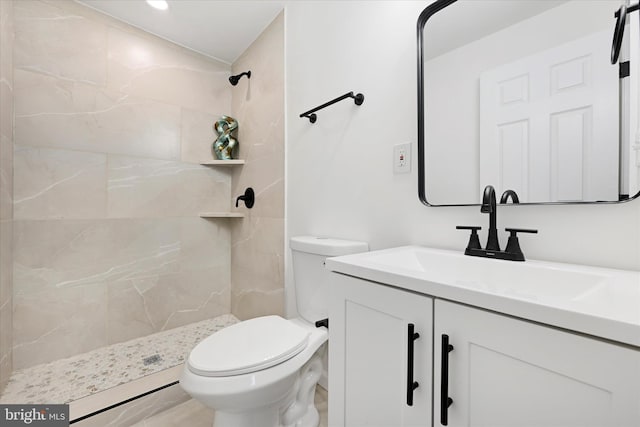 bathroom with toilet, vanity, and a tile shower