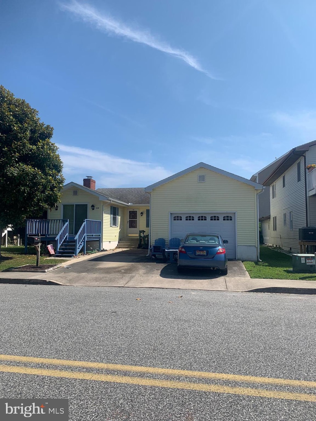 view of front facade with driveway, an attached garage, and central AC