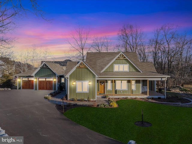 view of front of home featuring covered porch, a lawn, and a garage