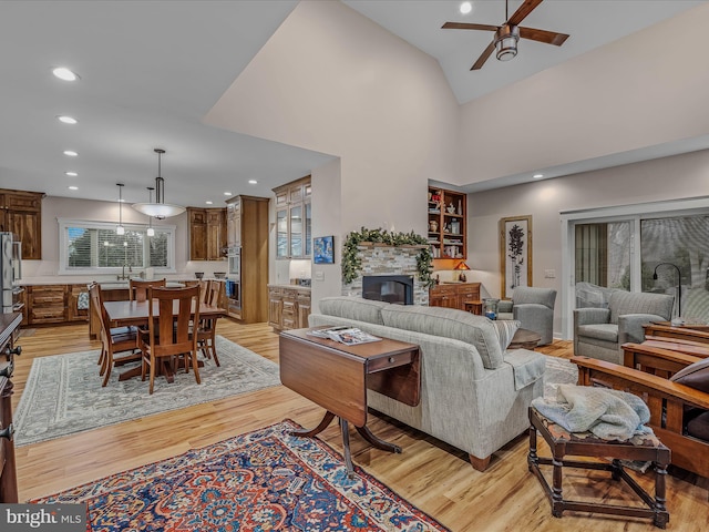 living room with a fireplace, ceiling fan, light hardwood / wood-style floors, and sink