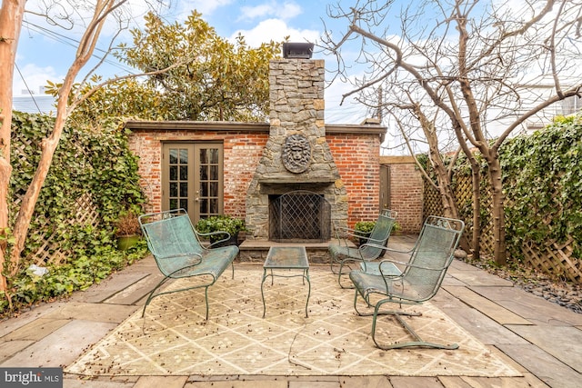 view of patio / terrace featuring an outdoor brick fireplace, fence, and french doors