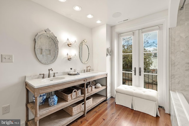 full bath with double vanity, wood finished floors, a sink, and visible vents