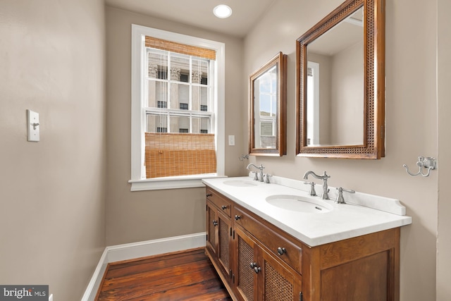 bathroom with double vanity, a sink, baseboards, and wood finished floors