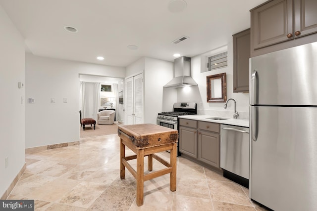 kitchen with wall chimney exhaust hood, stainless steel appliances, light countertops, gray cabinetry, and a sink