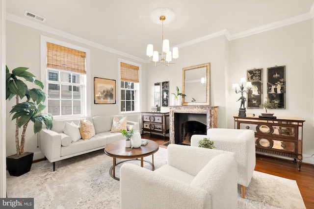 living room with crown molding, wood finished floors, visible vents, a high end fireplace, and an inviting chandelier