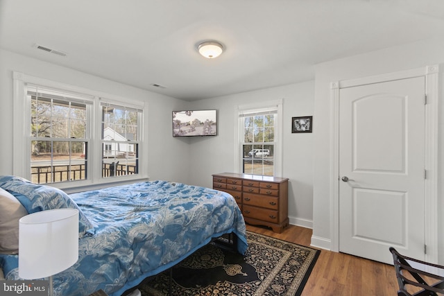 bedroom featuring wood finished floors, visible vents, and baseboards