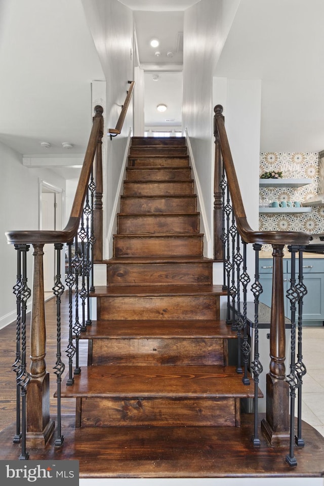 staircase featuring baseboards and wood finished floors