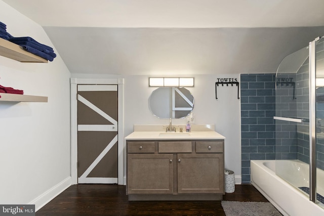 bathroom with vaulted ceiling, vanity, baseboards, and wood finished floors