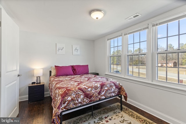 bedroom with dark wood finished floors, visible vents, and baseboards