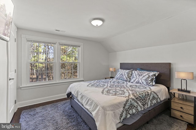 bedroom featuring lofted ceiling, dark wood finished floors, visible vents, and baseboards