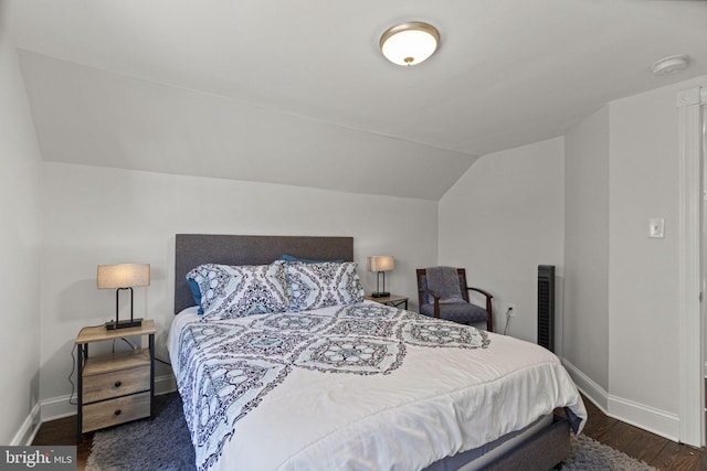 bedroom with lofted ceiling, baseboards, and dark wood-style flooring