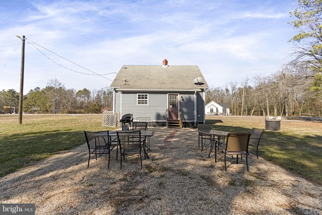 back of property featuring entry steps and a yard