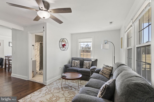 living area featuring baseboards, visible vents, ceiling fan, and dark wood-type flooring