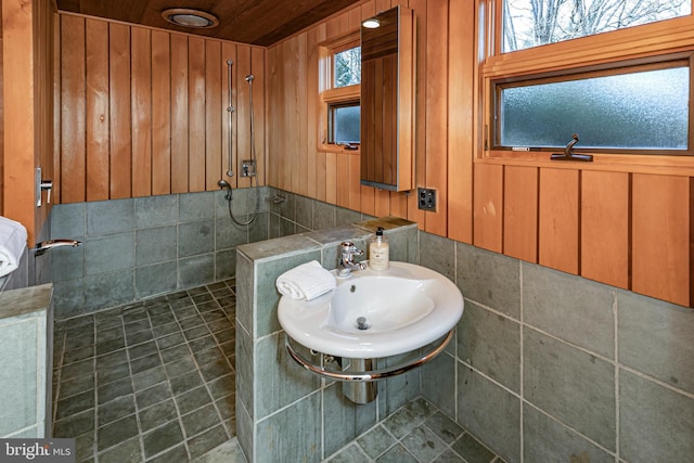 bathroom with tile patterned flooring, walk in shower, wood walls, wooden ceiling, and sink