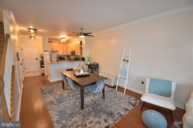 dining room with ceiling fan, baseboards, stairs, ornamental molding, and dark wood-style floors