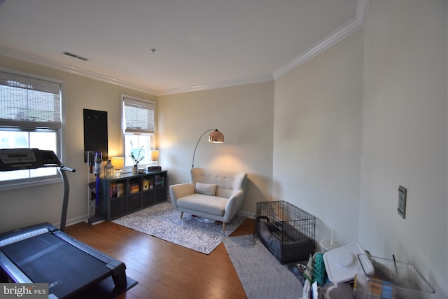 living area featuring baseboards, visible vents, ornamental molding, and wood finished floors