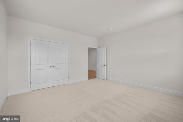 unfurnished bedroom with light carpet and a closet