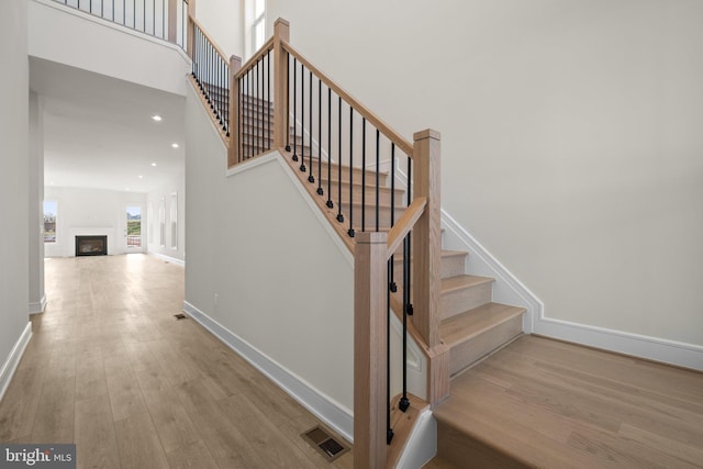 stairs featuring a high ceiling and wood-type flooring