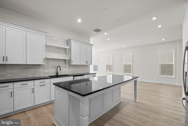 kitchen featuring white cabinets, light wood-type flooring, sink, and decorative backsplash