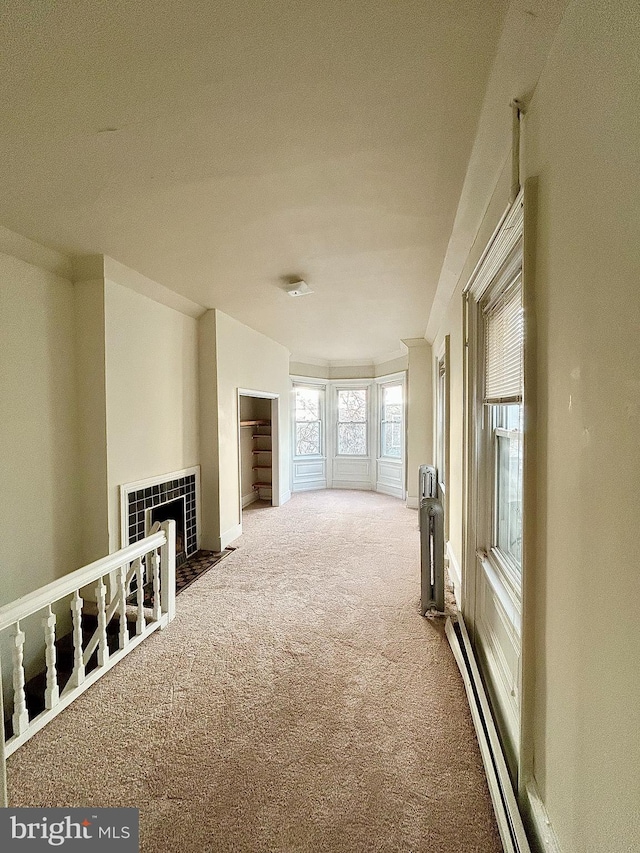 unfurnished living room with ornamental molding, baseboard heating, carpet, and a fireplace