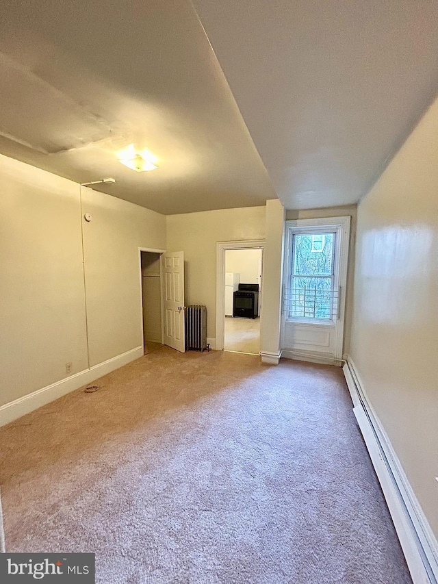 empty room with carpet floors, a baseboard radiator, radiator, and baseboards