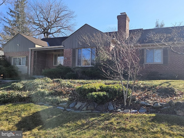 view of front facade with a front yard, brick siding, and a chimney