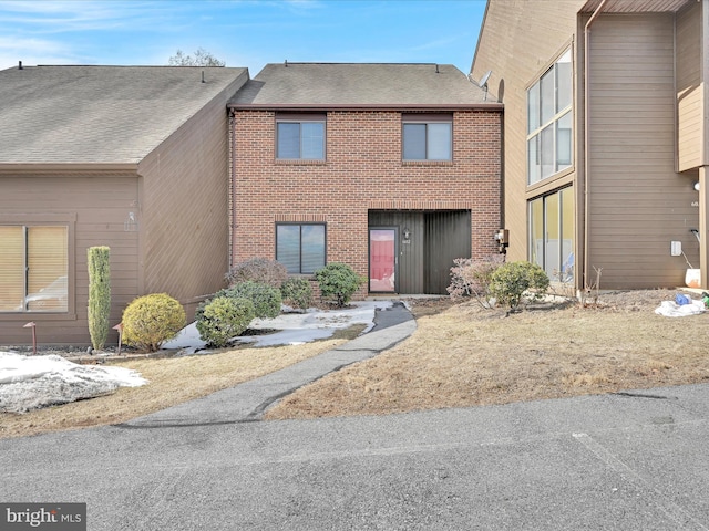 townhome / multi-family property with brick siding and roof with shingles