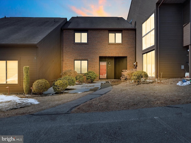 view of front of home featuring brick siding and a shingled roof