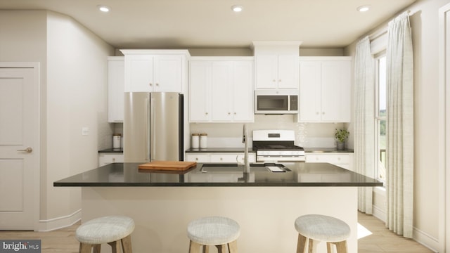 kitchen with stainless steel appliances, dark countertops, a breakfast bar area, and white cabinets