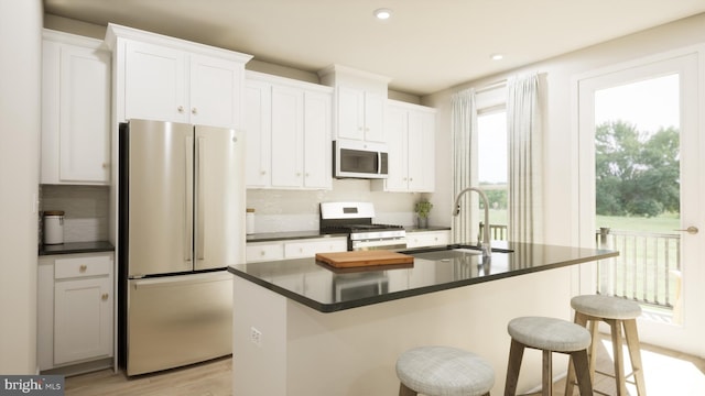 kitchen featuring white microwave, stainless steel range with gas stovetop, freestanding refrigerator, a sink, and dark countertops