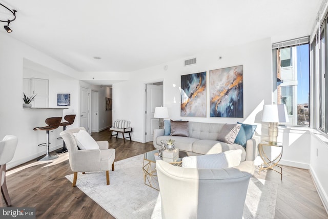 living area featuring visible vents, baseboards, and wood finished floors