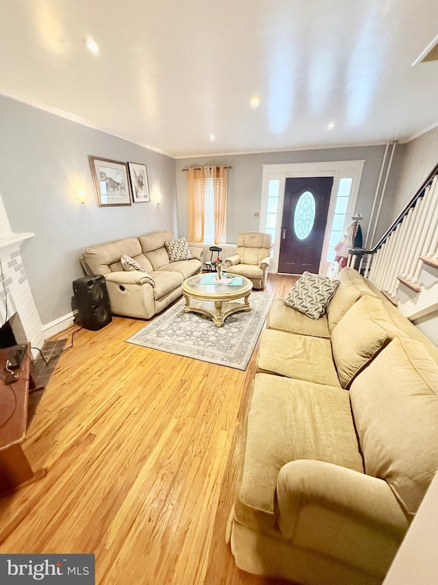 living room featuring ornamental molding, hardwood / wood-style flooring, and a brick fireplace