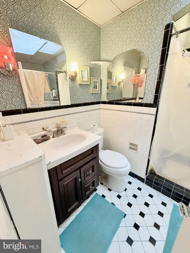 bathroom with curtained shower, toilet, tile walls, and vanity