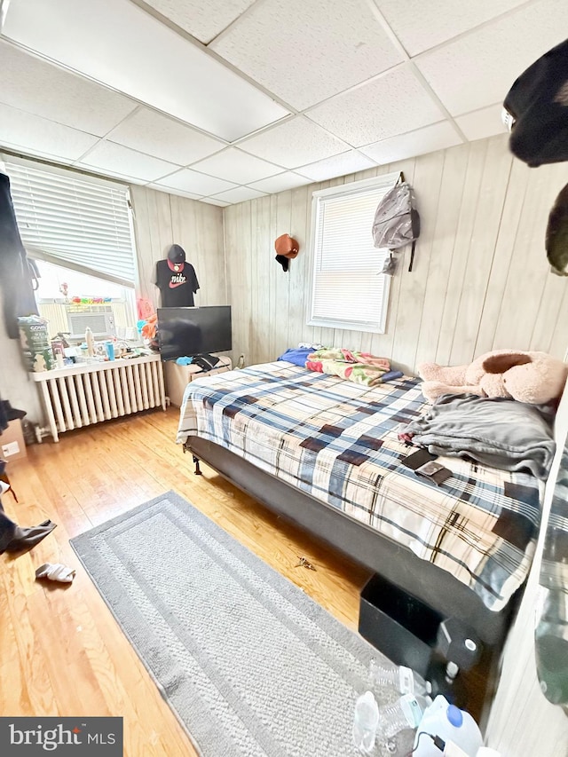 bedroom featuring a drop ceiling and wood-type flooring