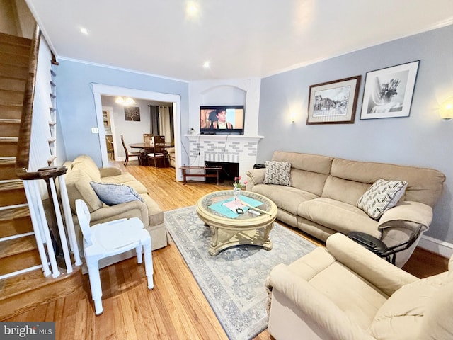 living room with a fireplace, ornamental molding, and wood-type flooring