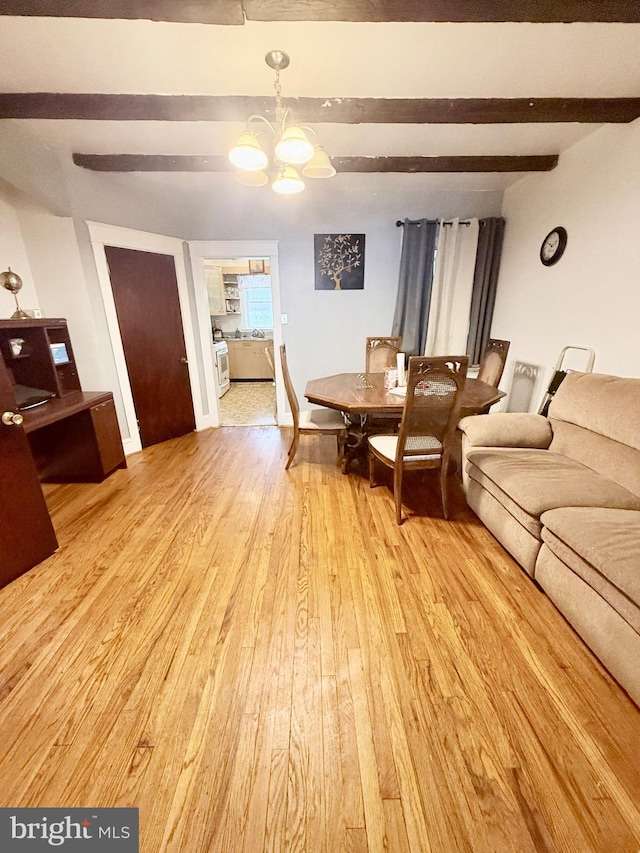 living room featuring light hardwood / wood-style floors, an inviting chandelier, and beam ceiling