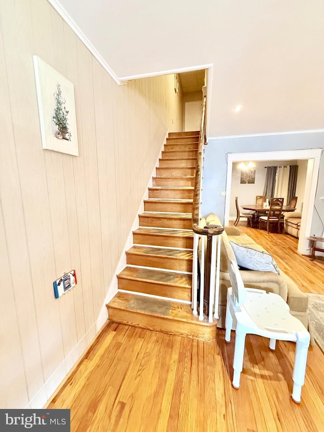 stairway with ornamental molding and wood-type flooring