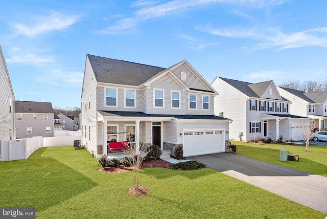 traditional-style home with driveway, a front yard, fence, and a residential view