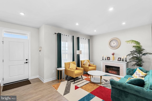 living area with light wood-type flooring, recessed lighting, baseboards, and a glass covered fireplace