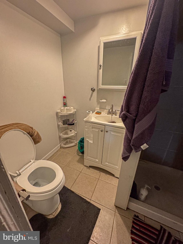 bathroom with tile patterned flooring, toilet, vanity, baseboards, and a shower stall