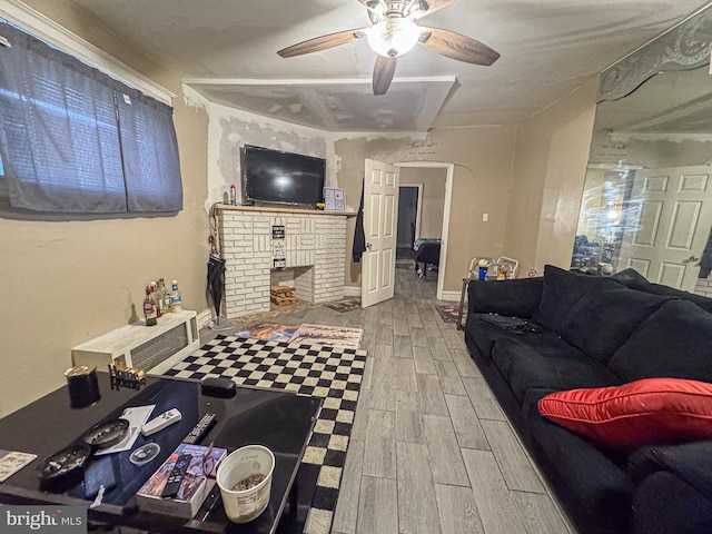 living area with arched walkways, a ceiling fan, baseboards, a brick fireplace, and wood tiled floor