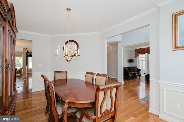 dining room with light wood-type flooring, crown molding, and wainscoting