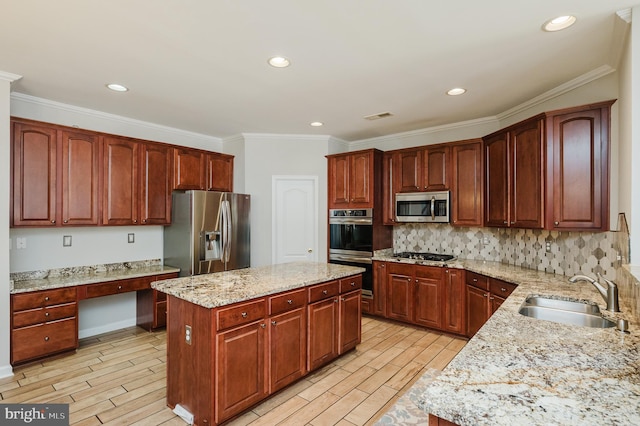 kitchen featuring built in study area, appliances with stainless steel finishes, light stone counters, a center island, and a sink