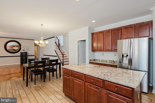 kitchen featuring a center island, decorative light fixtures, light wood finished floors, ornamental molding, and stainless steel fridge with ice dispenser