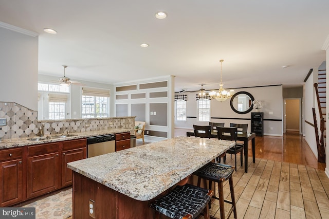 kitchen with decorative backsplash, a center island, light wood-type flooring, pendant lighting, and stainless steel dishwasher