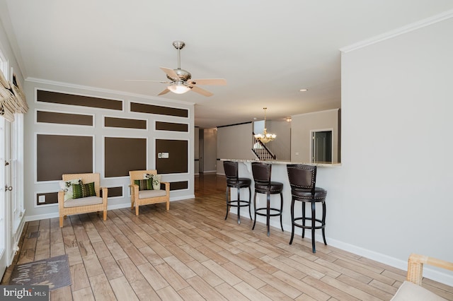 kitchen featuring a peninsula, light wood-style floors, a breakfast bar area, and crown molding